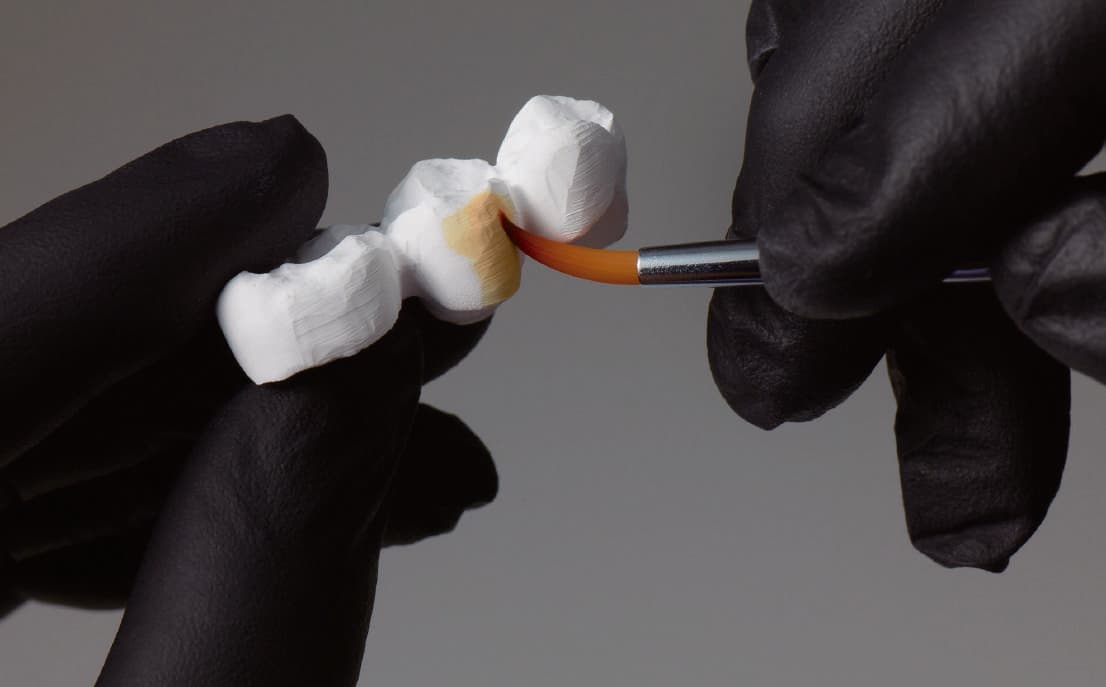 Lab technician staining a Perfit ZR restoration